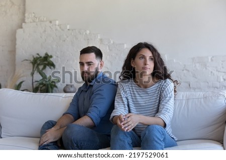 Silent couple sit on sofa staring aside after fight, avoid talk, look deep in thoughts about relationship break up, troubles in relations. Marriage, split, crisis, misunderstanding, quarrels concept Royalty-Free Stock Photo #2197529061