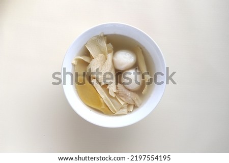 Indonesian traditional food named "Sup kembang tahu bakso ikan" i.e. tofu skin soup with fish meatballs served on plate isolated on white background
