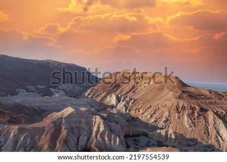 Cliffs at dusk and caves on the shores of the Dead Sea, Israel. Sunset on a large salt formation mountains range with fluffy clouds. Evening gold sunset sky over mountains Sodom and Gomorrah. Sunrise Royalty-Free Stock Photo #2197554539