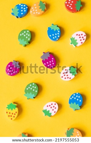 Colored wooden figures in the form of strawberries on a yellow background