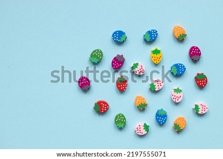Colored wooden figures in the form of strawberries on a blue background
