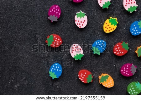 Colored wooden figures in the form of strawberries on a dark background