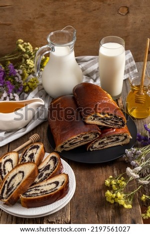 Roll with poppy seeds and a glass of milk. Food on the table. Sweet sweet pastries. Homemade simple yeast bun with filling. Breakfast on a wooden table. lactose and gluten. Honey spas