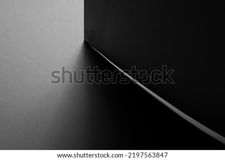 Dark grey carbon textured abstract geometric background with corner of sheets in hard light with thin light line of clearance in graphic minimalist monochrome business style, top view, copy space.