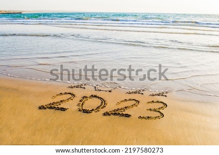 Happy New Year 2023 text on sea beach. Abstract background photo of coming new year 2023 and leaving year of 2022