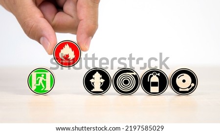 Hand choose wooden toy stack with fire prevent icon on door exit sing or fire escape with fire extinguisher and emergency prevention or protection symbol for safety first and rescue.