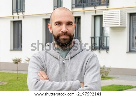 Portrait of a bald man 30-35 years old against the background of new beautiful multi-storey buildings, looking into the camera. Royalty-Free Stock Photo #2197592141