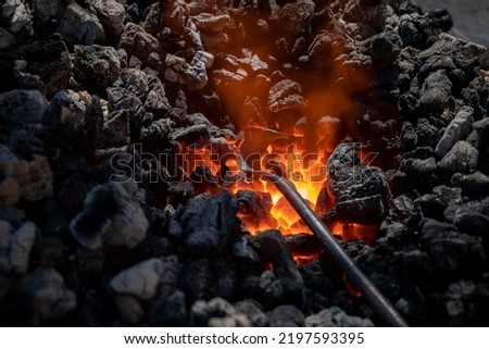 Medieval furnace with burning coal and an iron being heated so that after heating it can be worked Royalty-Free Stock Photo #2197593395