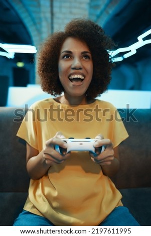 A young woman plays on a console. The emotion of victory, excitement and joy. High quality photo