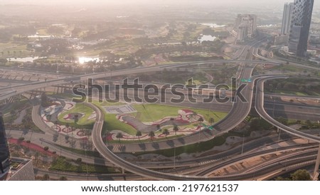 Huge highway crossroad junction between JLT district and Dubai Marina during sunrise intersected by Sheikh Zayed Road aerial morning timelapse. Golf course with sun reflected from water surface