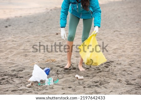 Crop unrecognizable female volunteer cleaning beach from garbage 