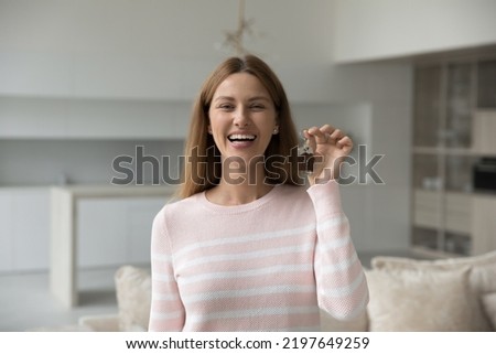 Cheerful homeowner woman holding key from new apartment, posing at just renovated home after moving, smiling, laughing. Happy agent offering real estate service, mortgage, house buying help