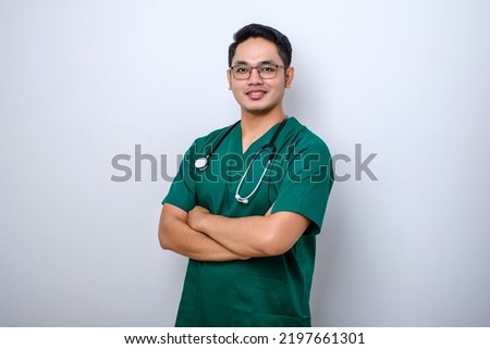 Professional good-looking asian doctor, medical worker in glasses and scrubs, cross arms and smiling, isolated over white background