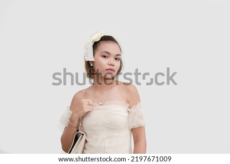 A young woman wearing a white lace dress and a bow on her hair standing proud isolated on a white background.