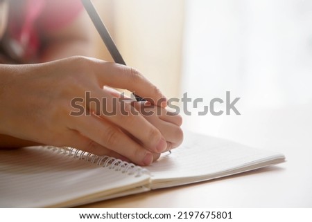 Mother hand and child hand writing on the book; Mom teaching child how to write Royalty-Free Stock Photo #2197675801
