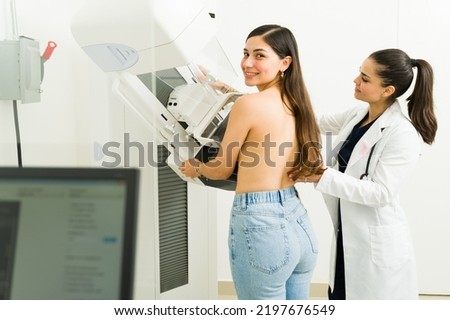 Cheerful beautiful woman smiling and looking at the camera while getting a mammogram at the diagnostic center to prevent breast cancer