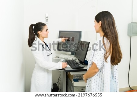 Caucasian female radiologist showing the medical results of the mammography to a young female patient to check for breast cancer
