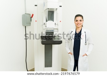 Cheerful female doctor smiling in front of the mammography x-ray at the imaging diagnostic center or hospital