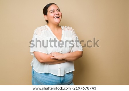 Excited plus size woman laughing and having fun feeling positive emotions in front of a studio background Royalty-Free Stock Photo #2197678743