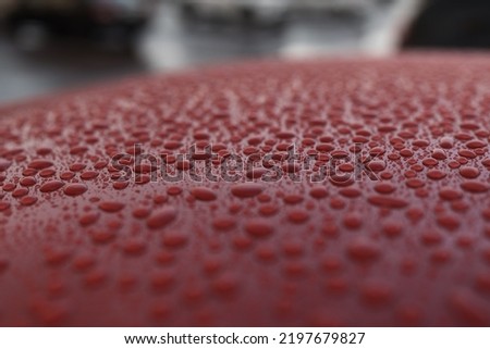 Closeup wet red car paint surface with hydrophobic ceramic coating, shallow focus