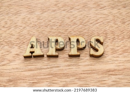 Set of wooden letter spelling the word APPS on wooden background.