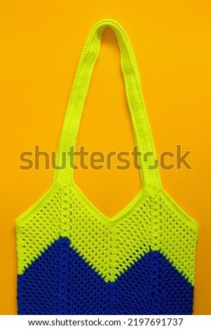 Blue lemon crochet bag on a yellow background. Crochet net bag with wave pattern. Eco friendly shopping concept. Top view.