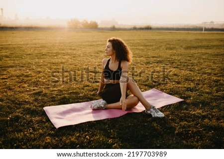 sports woman in the morning in a foggy city on the lawn at dawn practices yoga.