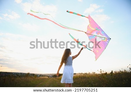 happy child girl with a kite running on meadow in summer in nature.