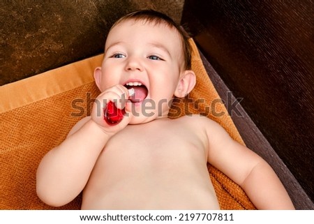 Happy toddler baby brushes his teeth with a toothbrush. A smiling child boy cleans his teeth with a brush on his own. Kid age one year