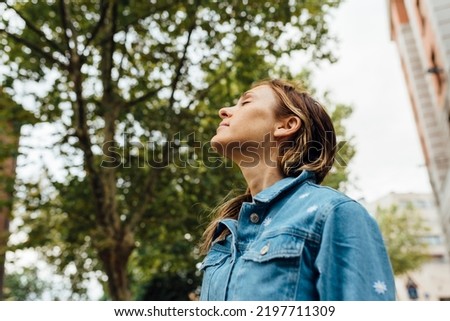 40 year old woman breathing fresh, clean air in a wooded park in the city. Pollution clean cities concept Royalty-Free Stock Photo #2197711309