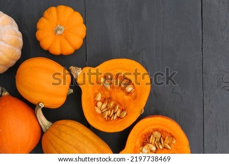 Pumpkins in the kitchen. Cut orange Hokkaido pumpkin with seeds on black wooden background.