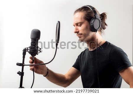 Man recording sound with microphone and headphones. In front of isolated background.