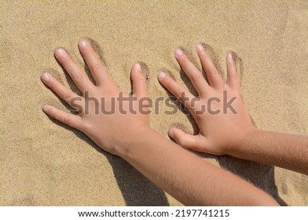 Child leaving handprints on sand outdoors, closeup. Fleeting time concept