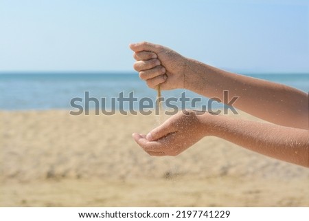 Child pouring sand from hands on beach, closeup. Fleeting time concept