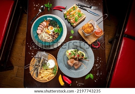 Different colorful meals on dark wooden table in the restaurant. Beautiful food background