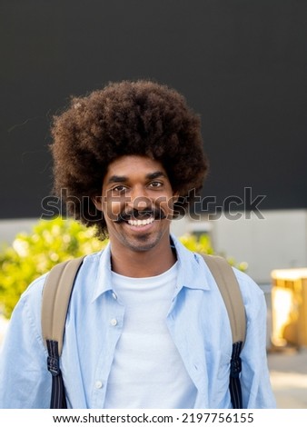 Vertical photo. Portrait of smiling african american man with mustache and afro hair looking at camera. Millennial man, freelancer