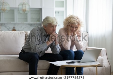 Concerned mature husband and wife frustrated about overspending family budget, money problems, sitting and paper bills, laptop, calculator at home, holding head, thinking over financial troubles Royalty-Free Stock Photo #2197756275