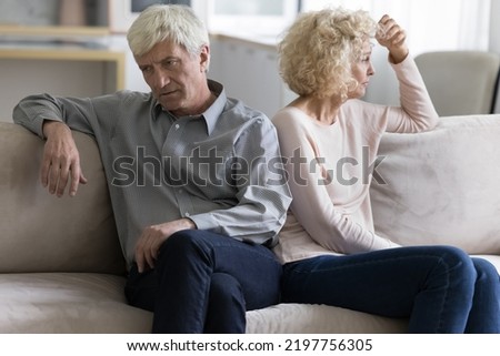 Offended annoyed upset mature older couple tired of each other, sitting on home sofa in silence, looking away, thinking over relationship problems, divorce, breakup, family crisis Royalty-Free Stock Photo #2197756305