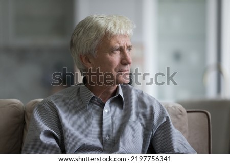 Thoughtful sad senior elder man sitting on home couch, looking away, thinking over health problems, feeling depressed, lonely, frustrated, coping with loss, grief, disease, mental disorder Royalty-Free Stock Photo #2197756341