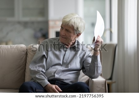 Angry annoyed older customer man holding paper documents, loan, insurance agreement, bank notice. Cheated investor feeling frustrated, mad about bad terms, conditions, money loss Royalty-Free Stock Photo #2197756395