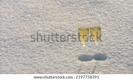 Photography of two glasses with golden champagne. Sunny winter day. White snow as background. Concept of holidays. Panoramic image