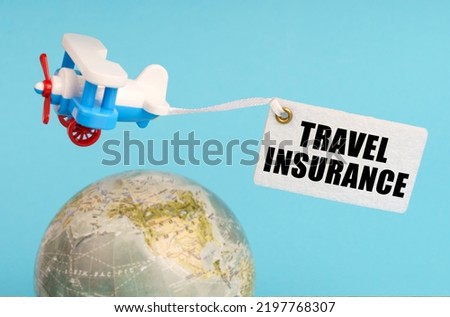 Travel and business concept. On a blue background, a globe and an airplane with a sign - Travel Insurance. Globe out of focus.