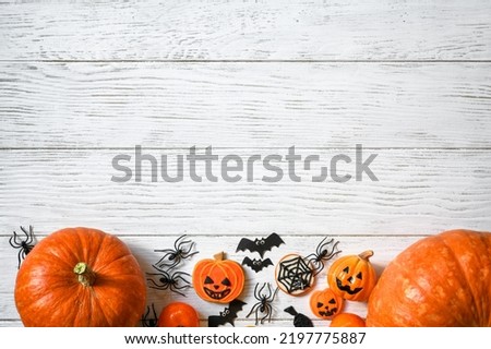 Halloween background, top view. Pumpkins and sweets on white wooden table, flat lay. Hallowen food and decorations on wood planks with space. Design, fall, October, Halloween, treat and trick concept
