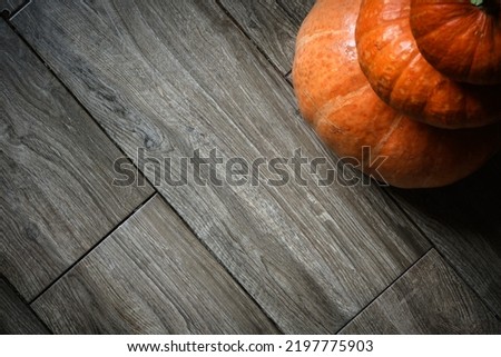 Stack of pumpkins on wood planks background for Halloween theme. Top view of orange vegetables tower on wooden floor and space. Halloween, thanksgiving, food, tile, farm, squash and kitchen concept.