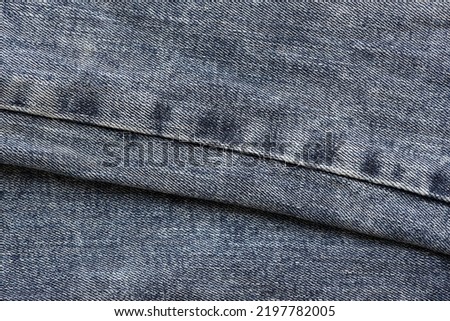 Detailed abstract texture of dark blue denim cloth. Background image of old used denim trousers fabric close up