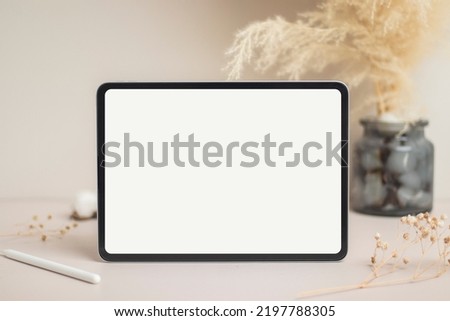 Tablet empty white screen with pencil mock-up. Cotton flower and dry leaves on beige background mockup for design Royalty-Free Stock Photo #2197788305