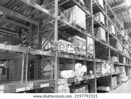 Black and white photo of the interior aisle of a warehouse with goods and boxes