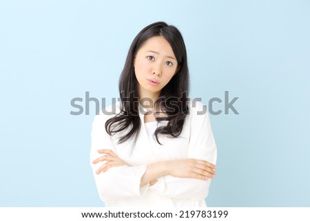 Portrait of a beautiful young woman thinking, isolated on blue background