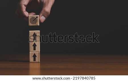 Business strategy. Businessman holding wooden cube with target board icon and arrow on wooden desk. Goals and planning for success in marketing business, achieve the objective concept. free copy space