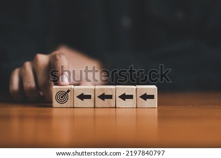 Business strategy. Businessman pointing wooden cube with target board icon and arrow on wooden desk. Goals and planning for success in marketing business, achieve the objective concept. free space.
